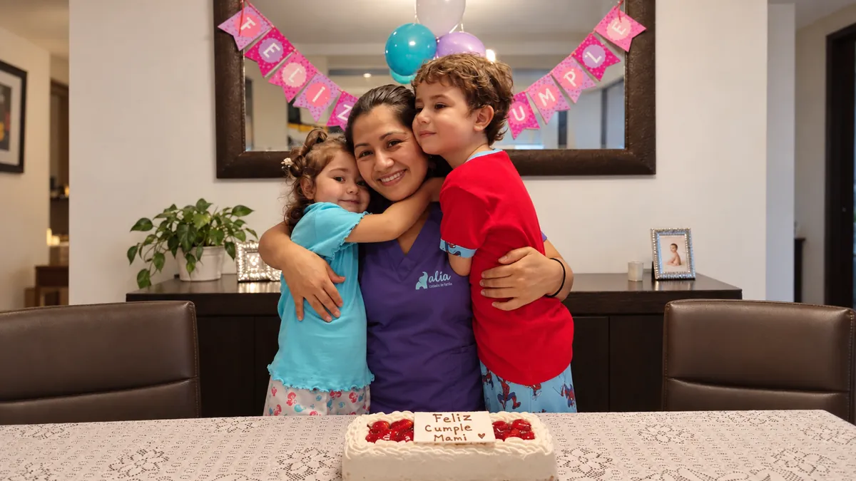 Una aliada abrazada por los dos niños que cuida, en el cumpleaños de la mamá